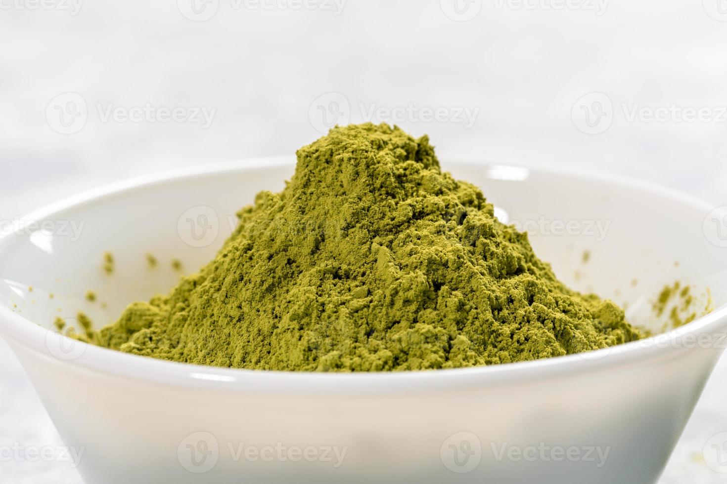 tigela branca de close-up cheia de pó de chá matcha japonês verde sobre fundo branco. fonte de antioxidantes para saudável. foto