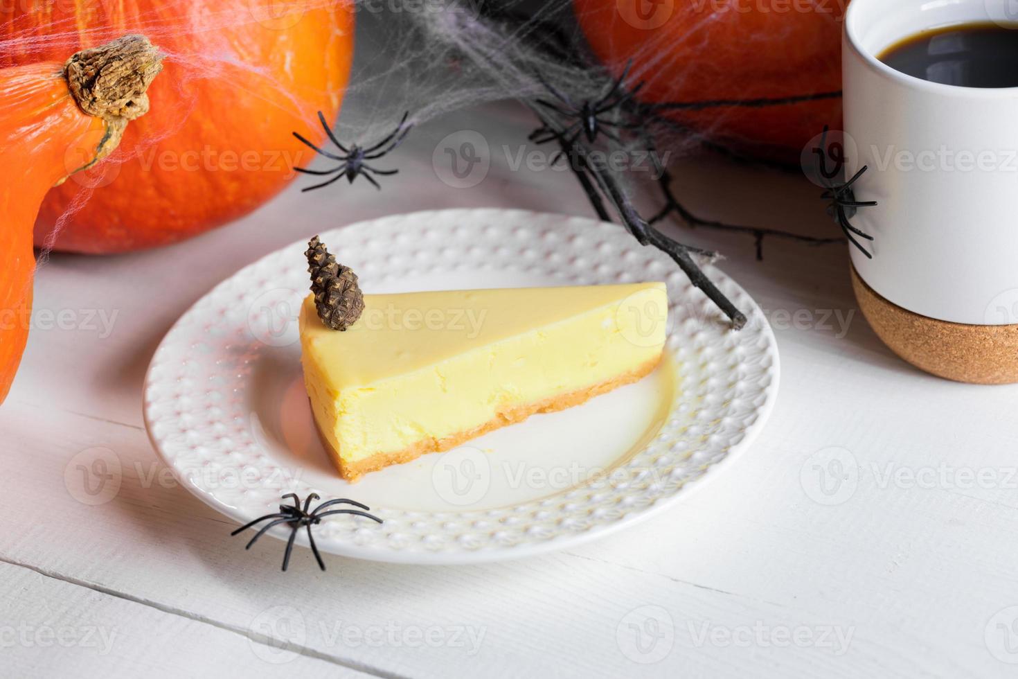 guloseimas de halloween - pedaço de torta de abóbora, xícara de chá ou café com abóboras e aranhas pretas em branco. foto