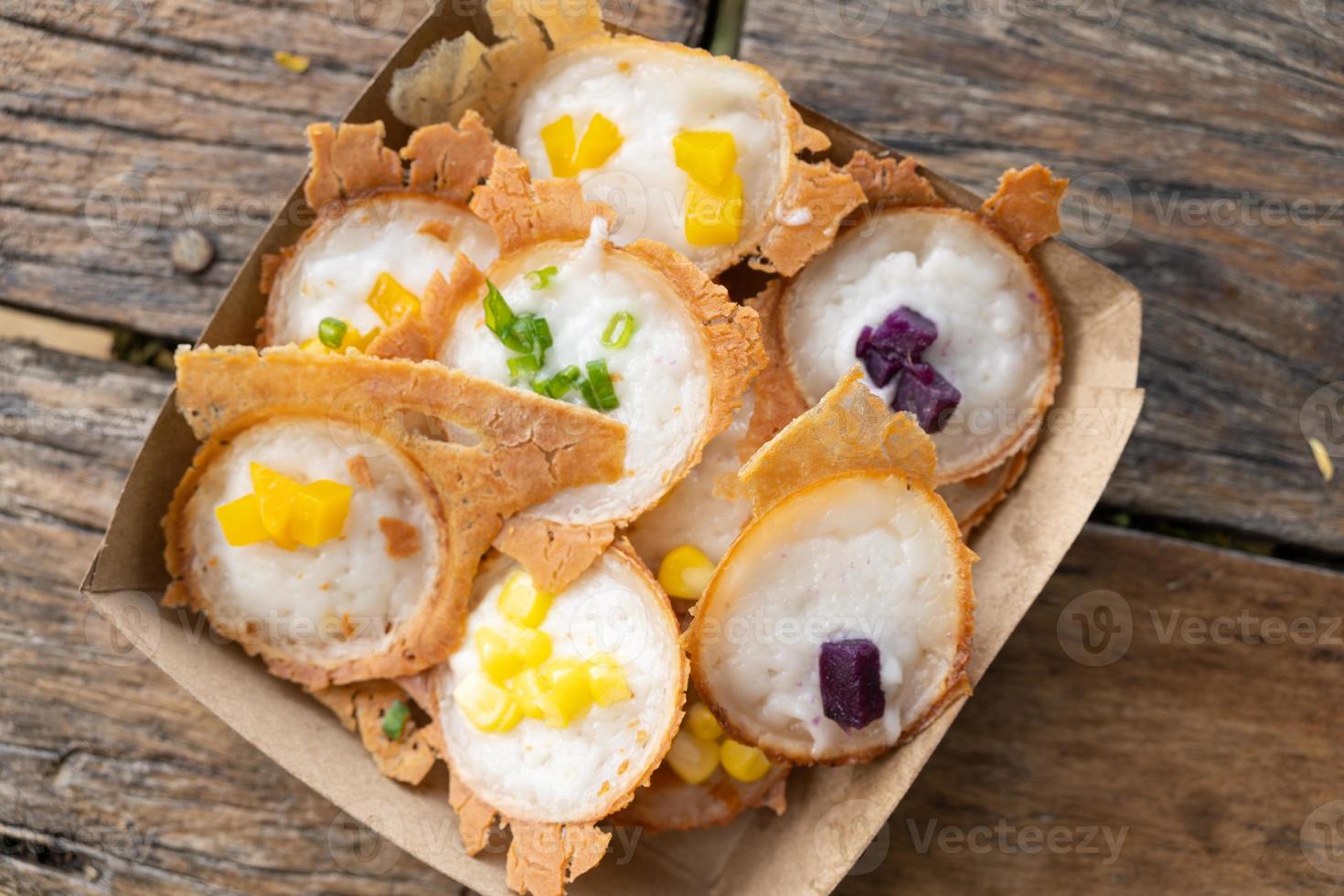 sobremesa tailandesa. khanom krok ou panqueca tailandesa de leite de coco em prato de papel. refeição doce. comida de rua na Tailândia. foto