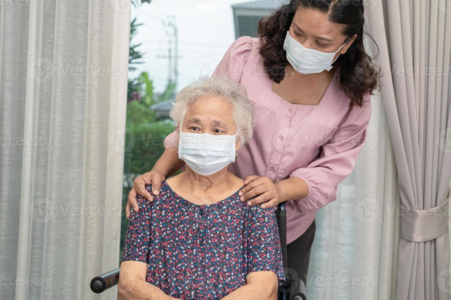 cuidador ajuda idosa asiática ou idosa sentada na cadeira de rodas e usando uma máscara facial para proteger a infecção de segurança covid19 coronavirus. foto