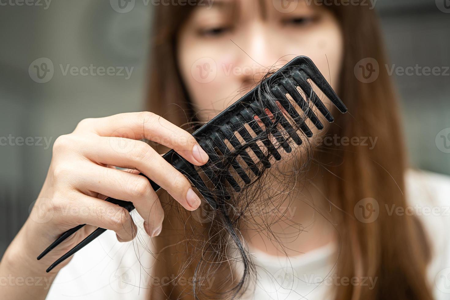 mulher asiática tem problema com perda de cabelo comprido anexar a escova de pente. foto