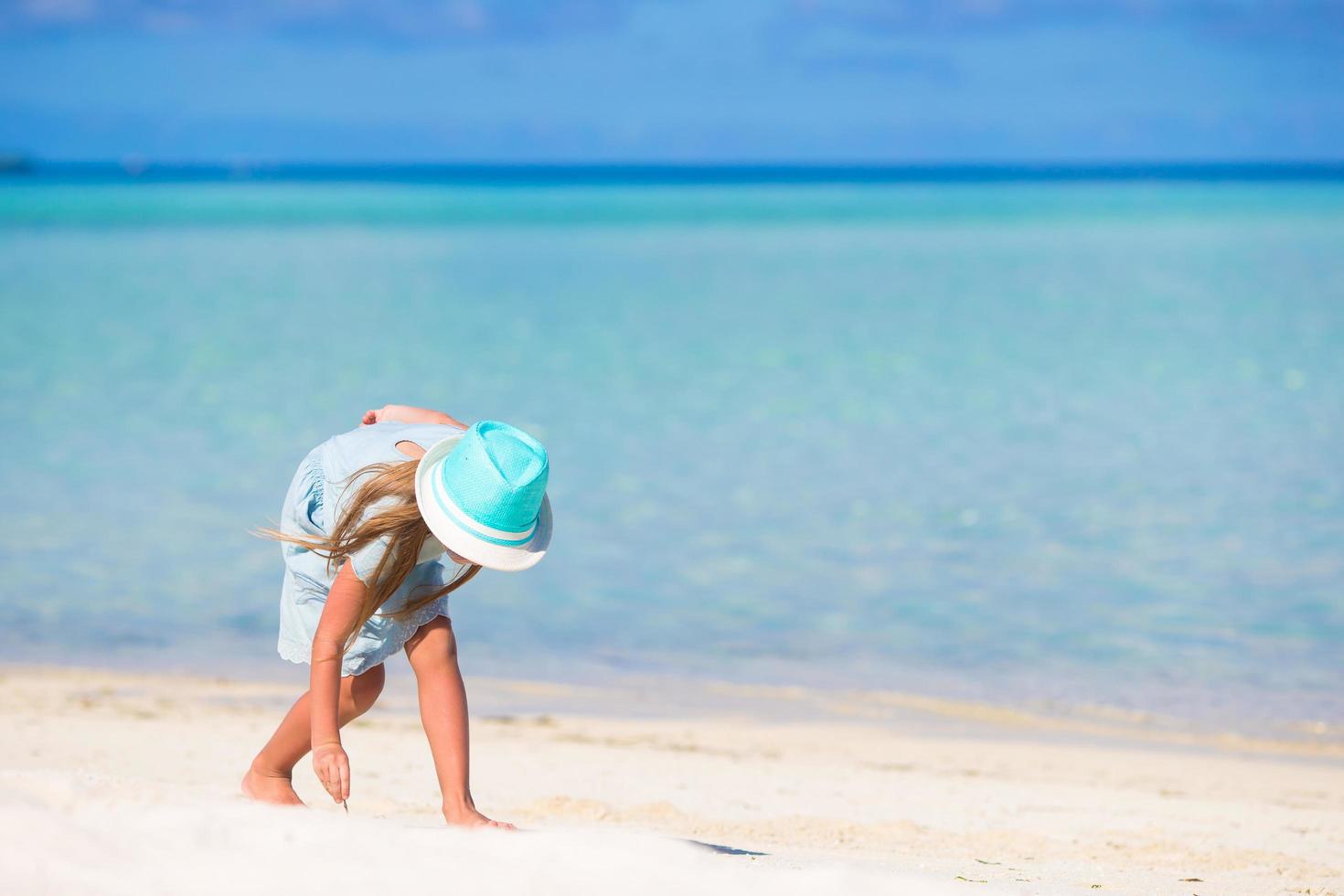 menina brincando na areia em uma praia foto