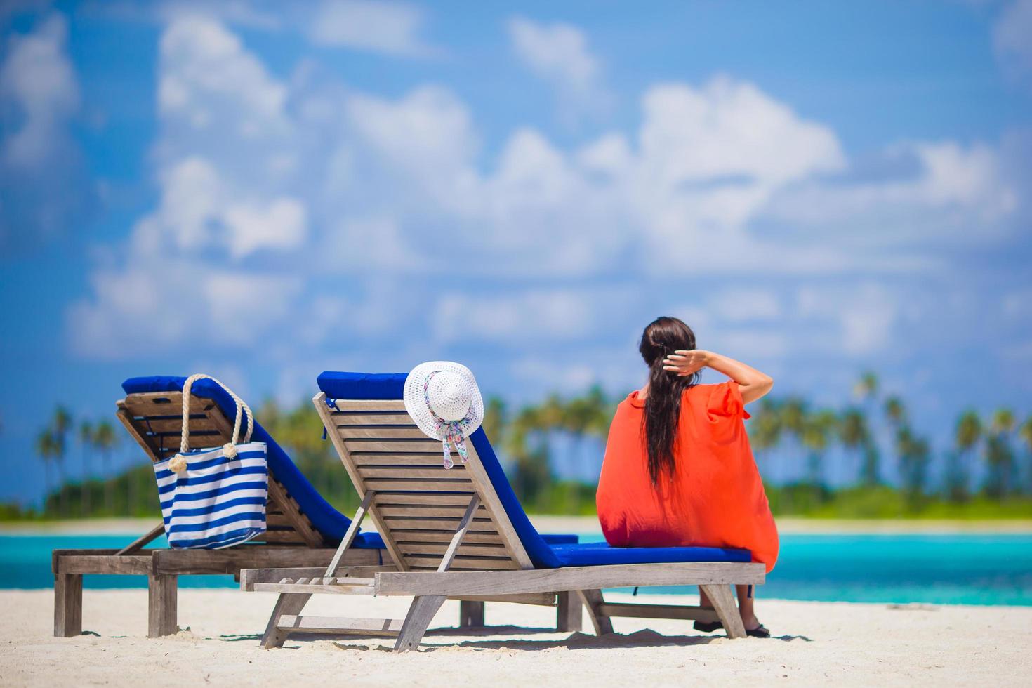 mulher sentada em uma cadeira na praia foto