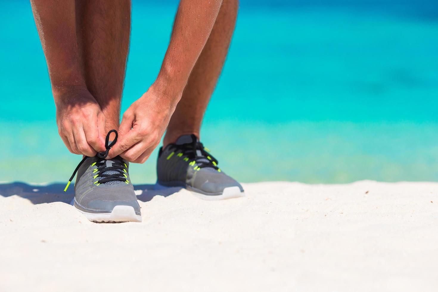 homem amarrando sapatos na praia foto