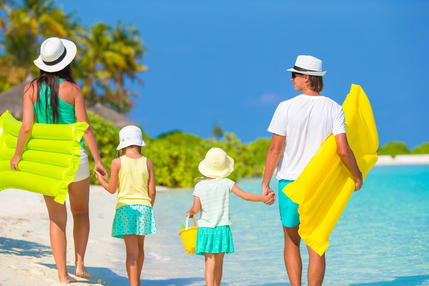 pais e filhos caminhando na praia foto