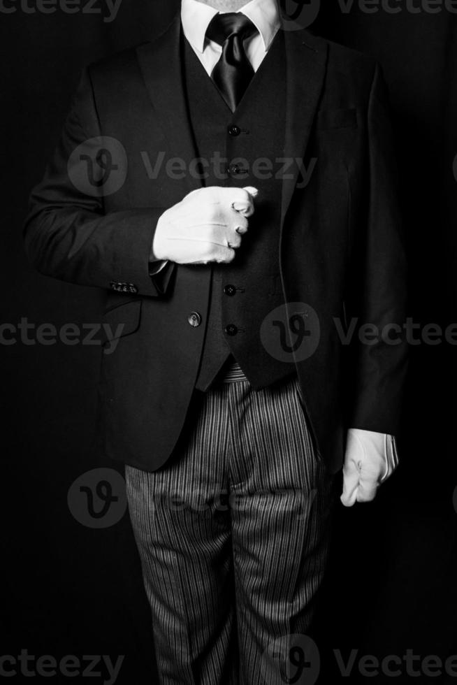 retrato preto e branco de mordomo ou servo em luvas brancas sobre fundo preto. indústria de serviços. hospitalidade profissional e cortesia foto
