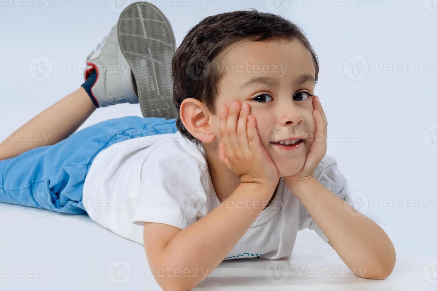 menino está deitado no chão, sorrindo e olhando para a câmera. foto