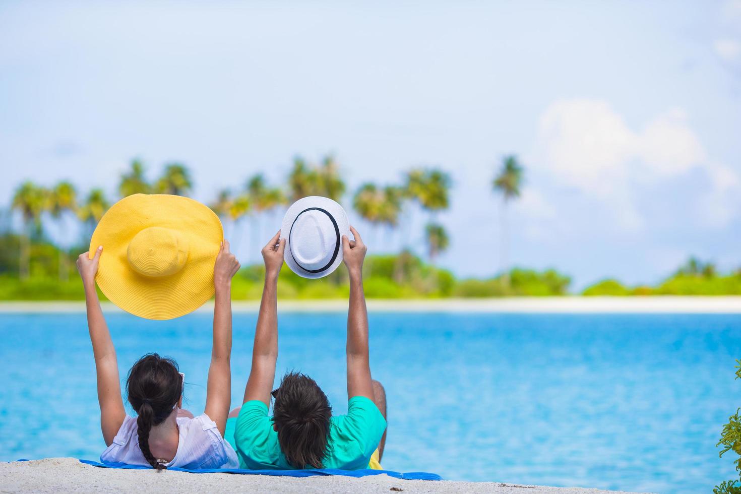 casal segurando chapéus em uma praia foto