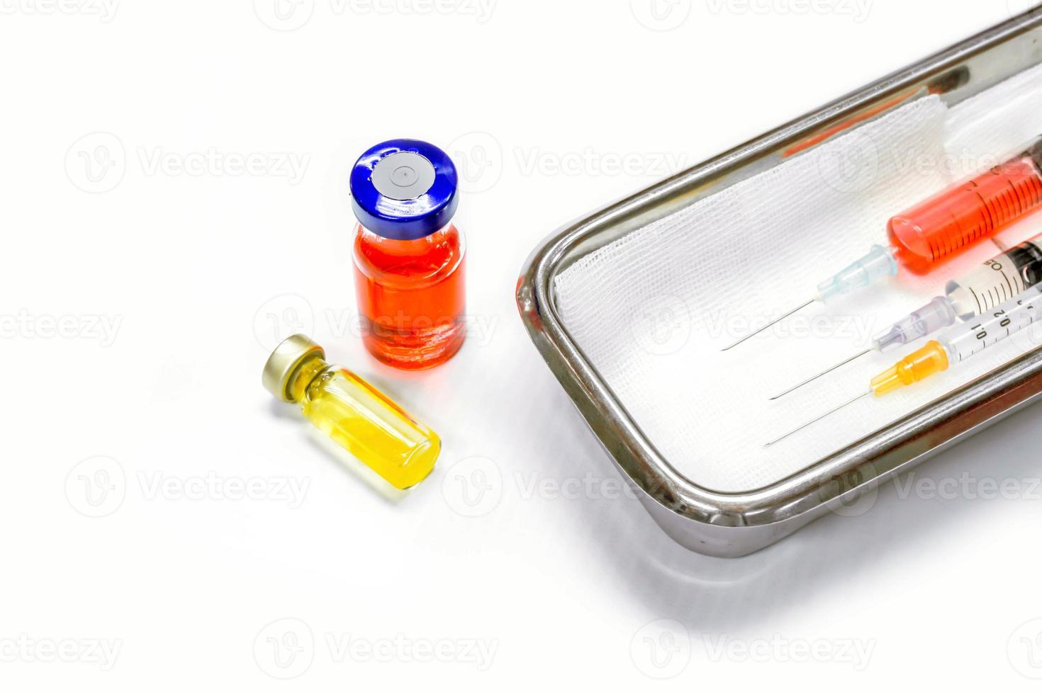 vacina em frascos e seringas de plástico com agulhas médicas colocadas em um recipiente médico de aço inoxidável para injeção pronta ao paciente em fundo branco. foto
