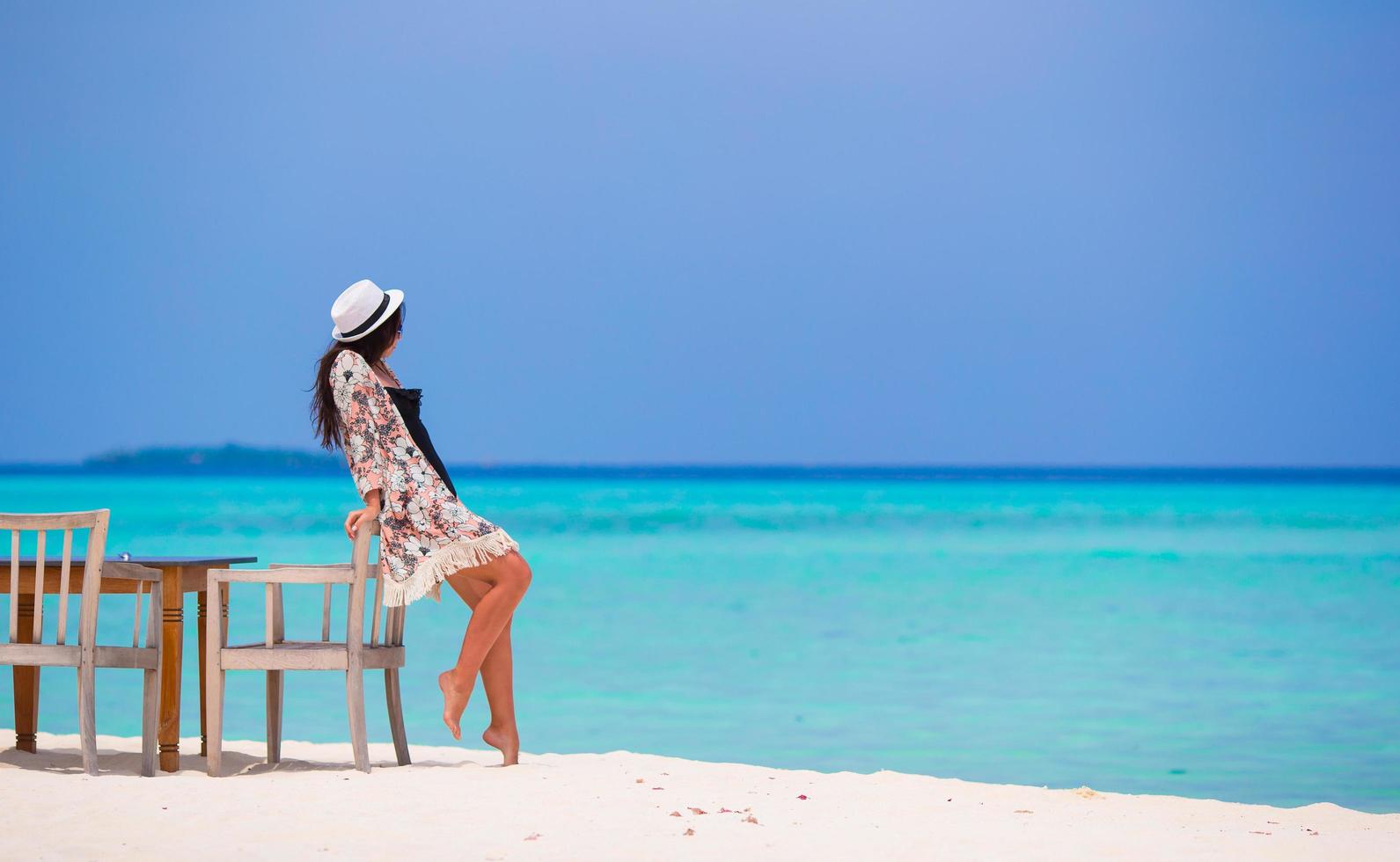 mulher encostada em uma cadeira na praia foto