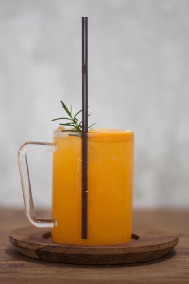 copo de suco de laranja em uma mesa de madeira foto