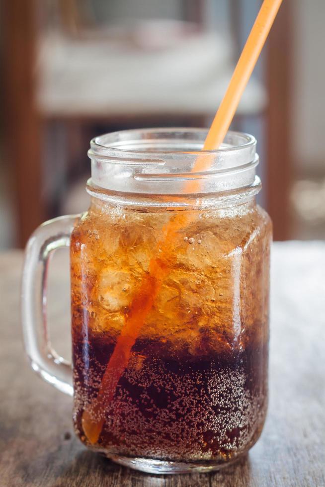 cola com gelo na mesa de madeira foto