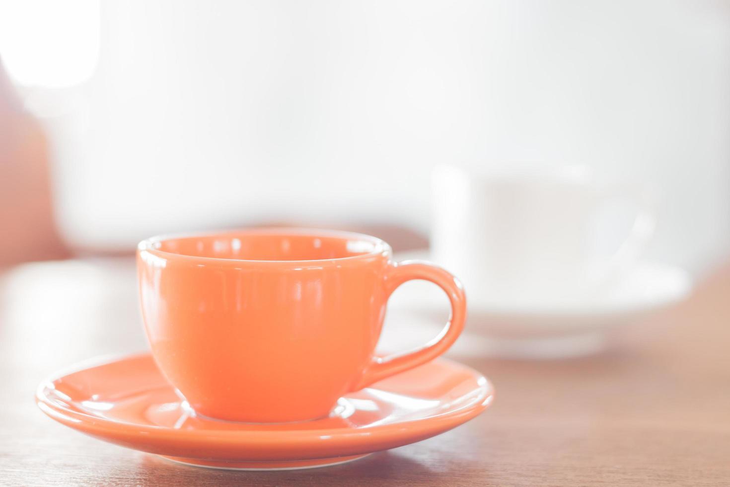 mini xícara de café laranja e xícara de café branco foto