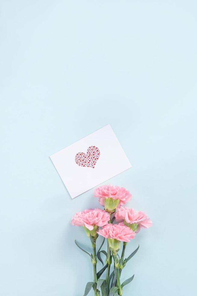 linda e elegante flor de cravo rosa sobre fundo de mesa azul claro brilhante, conceito de presente de flor para o dia das mães, vista superior, configuração plana, sobrecarga foto