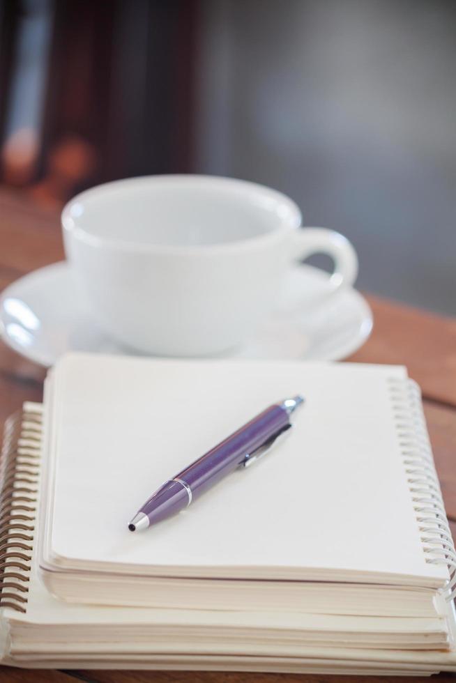 caneta roxa em um caderno com uma xícara de café foto