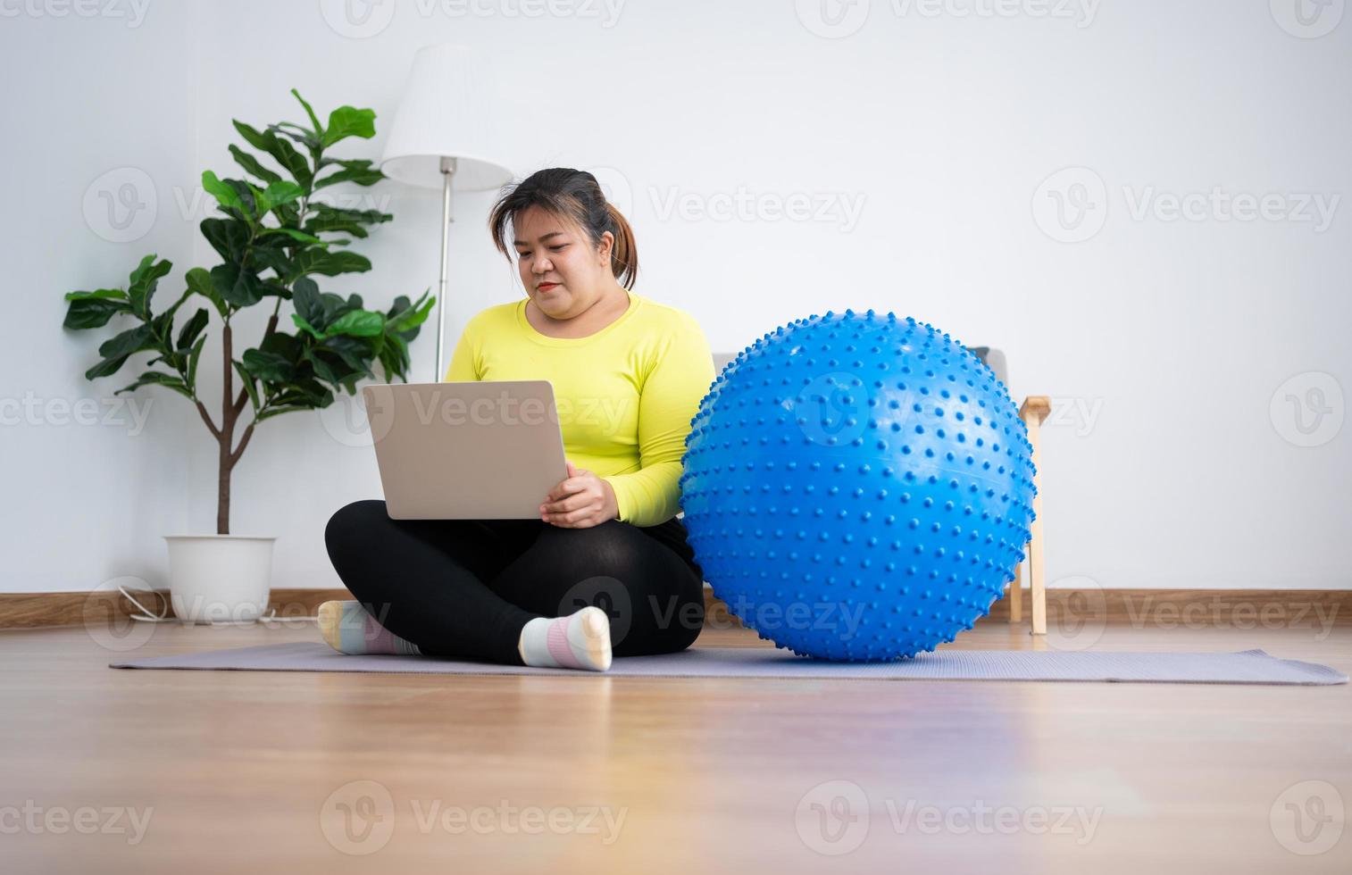 retrato plus size mulher usuário computador laptop para participar de aula de fitness para exercício com bola de fitness no ginásio em casa. tecnologia e comunicação, saúde e conceito de perda de peso. foto