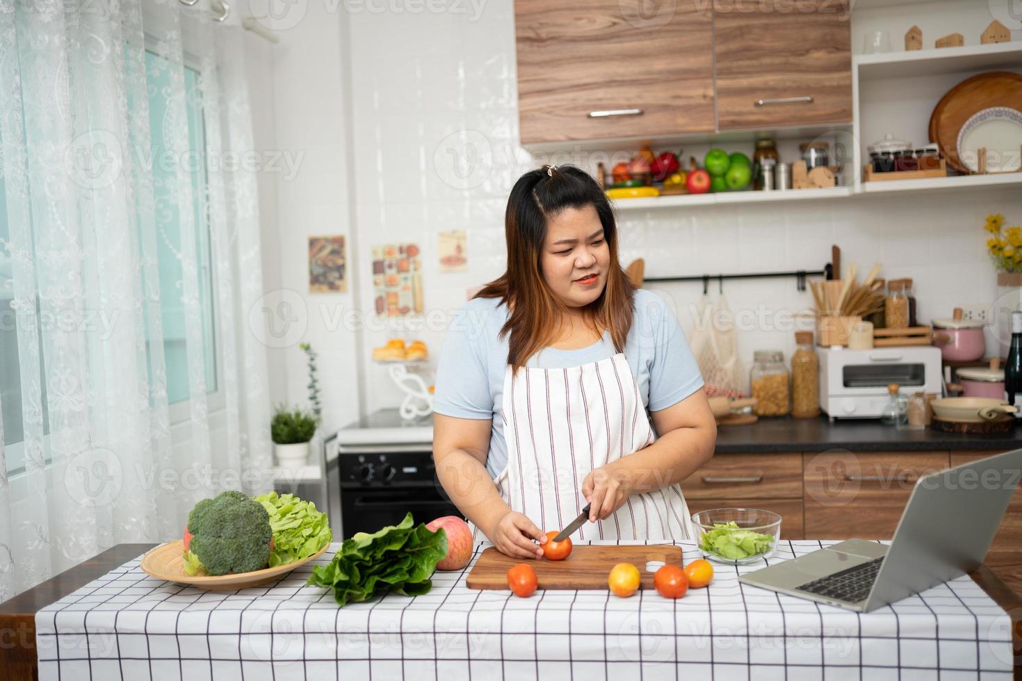 grávida asiática aprenda a cozinhar refeições saudáveis da internet na cozinha, mulheres gordas preparam uma salada de legumes para dieta alimentar e perdem peso. conceito de alimentação saudável foto