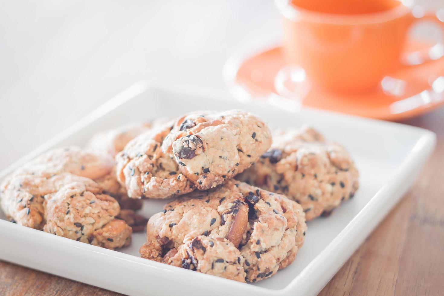 close-up de biscoitos de nozes com uma xícara de café laranja foto