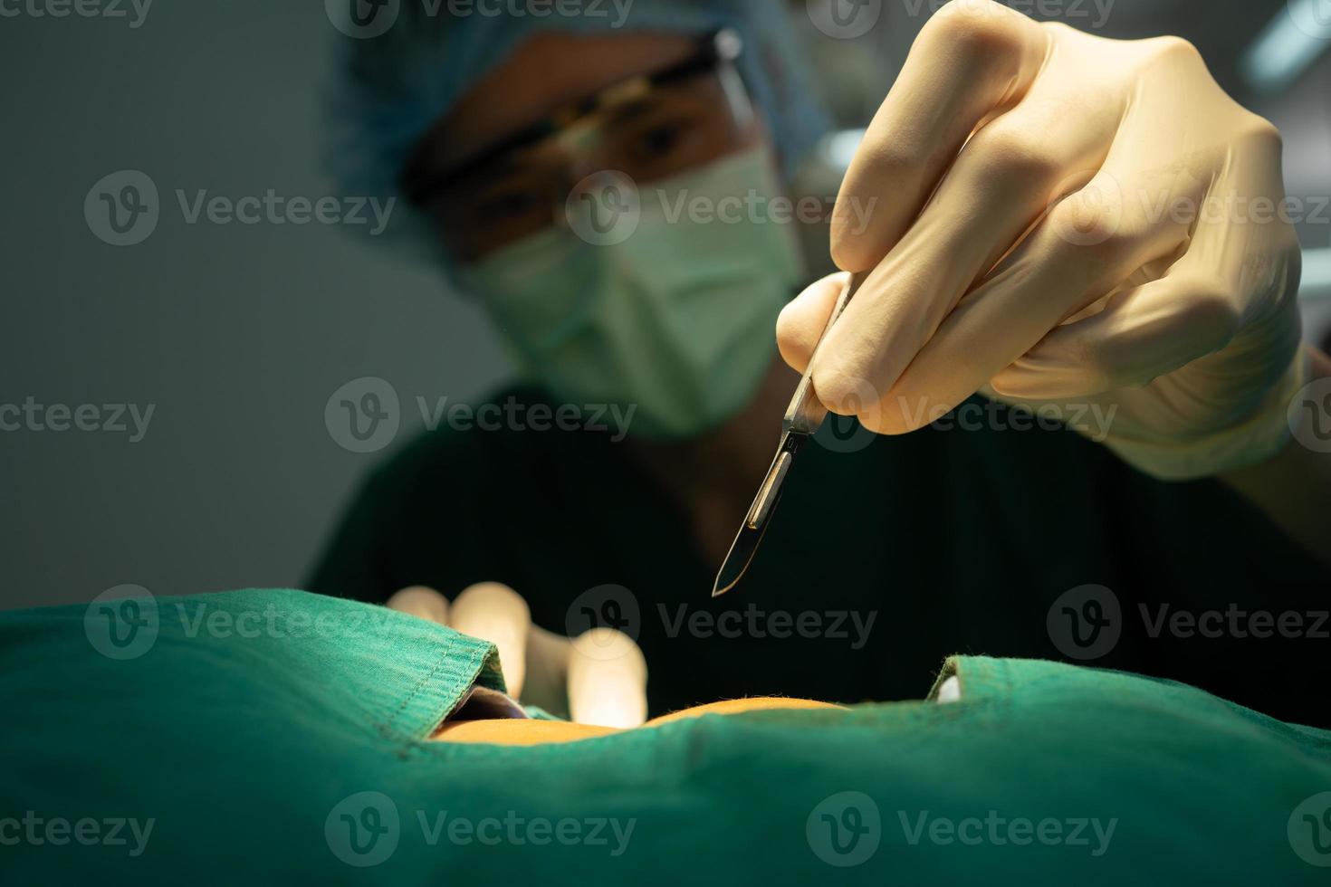 equipe de cirurgiões profissionais asiáticos realizando cirurgia na sala de cirurgia, cirurgião, assistentes e enfermeiras realizando cirurgia em um paciente, câncer de saúde e conceito de tratamento de doenças foto