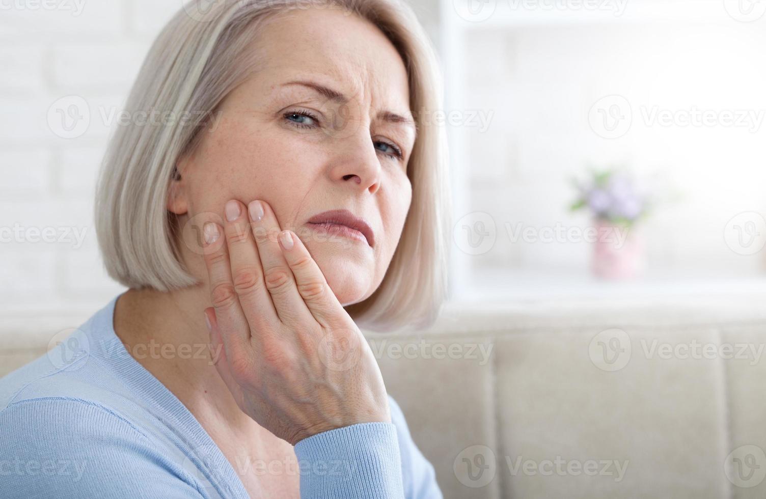 problema dos dentes. mulher sentindo dor de dente. closeup da bela meia-idade sofrendo de forte dor de dente. mulher atraente sentindo dor de dente dolorosa. conceito de saúde e cuidados dentários. alta resolução. foto