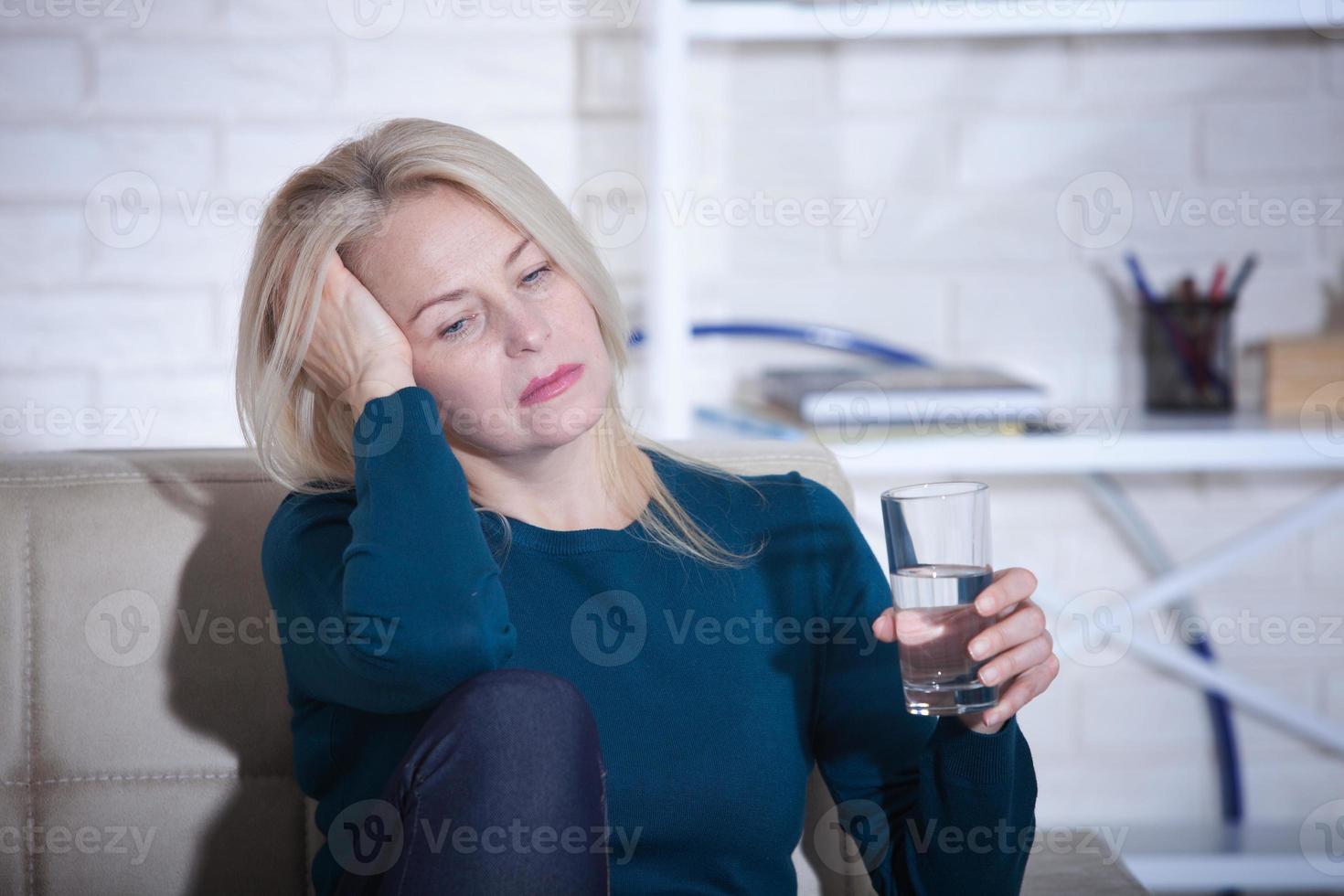 mulher bebendo conceito alcoólico de problemas sociais sentado em casa em um estado deprimido. mulher de meia idade segurando um copo pedindo ajuda. foto
