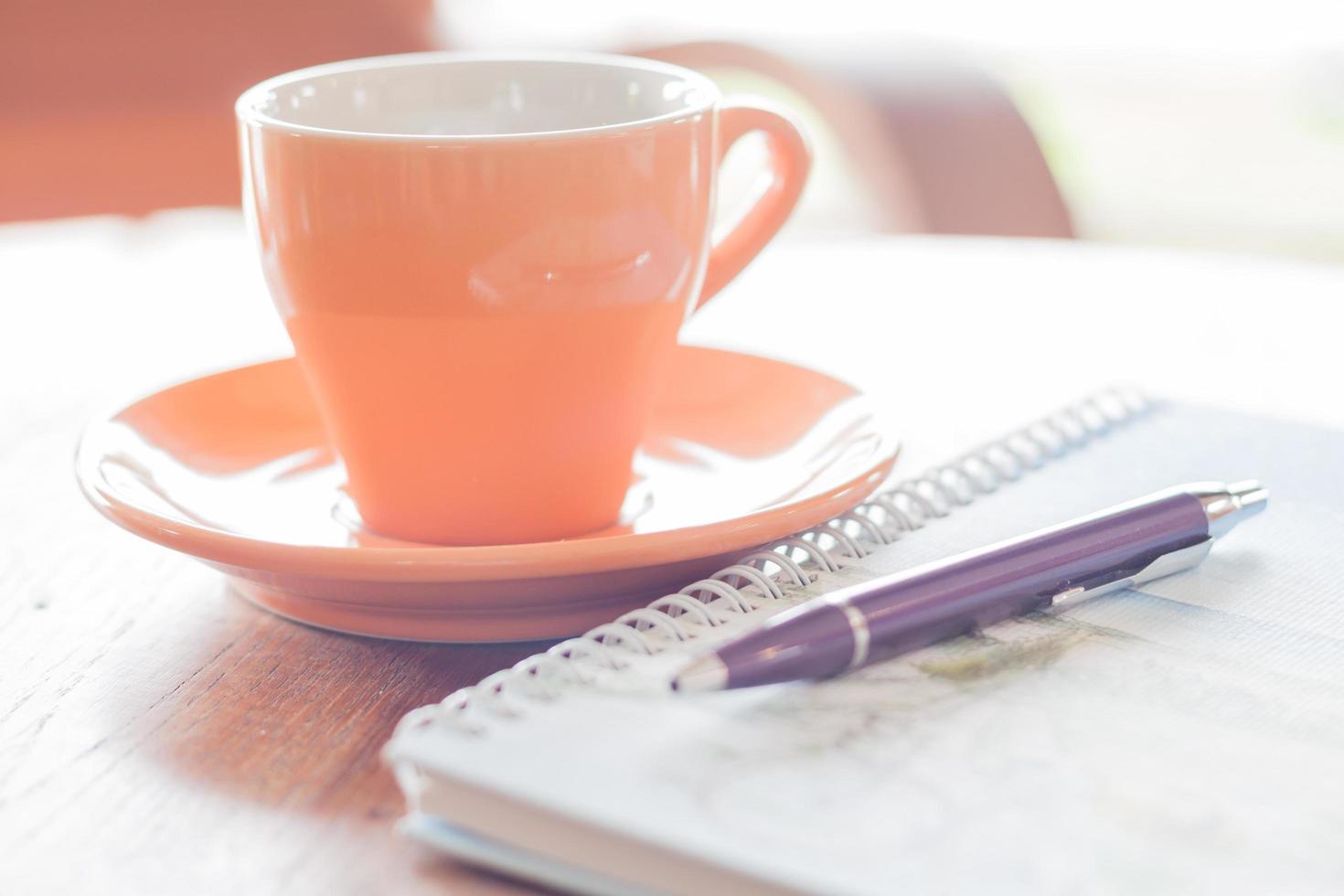 caneta e um caderno espiral com uma xícara de café foto