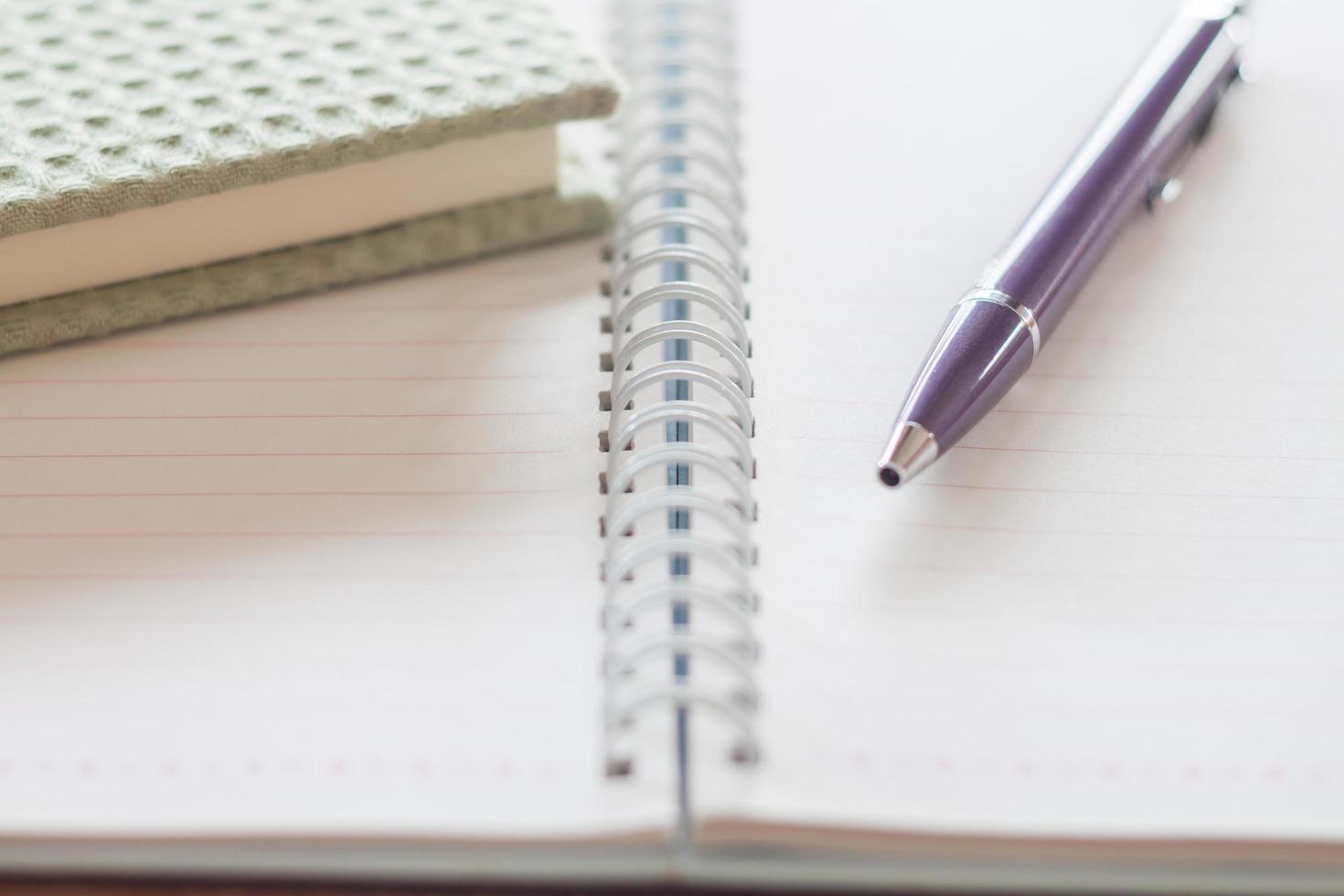 caneta e um caderno verde em um caderno espiral foto