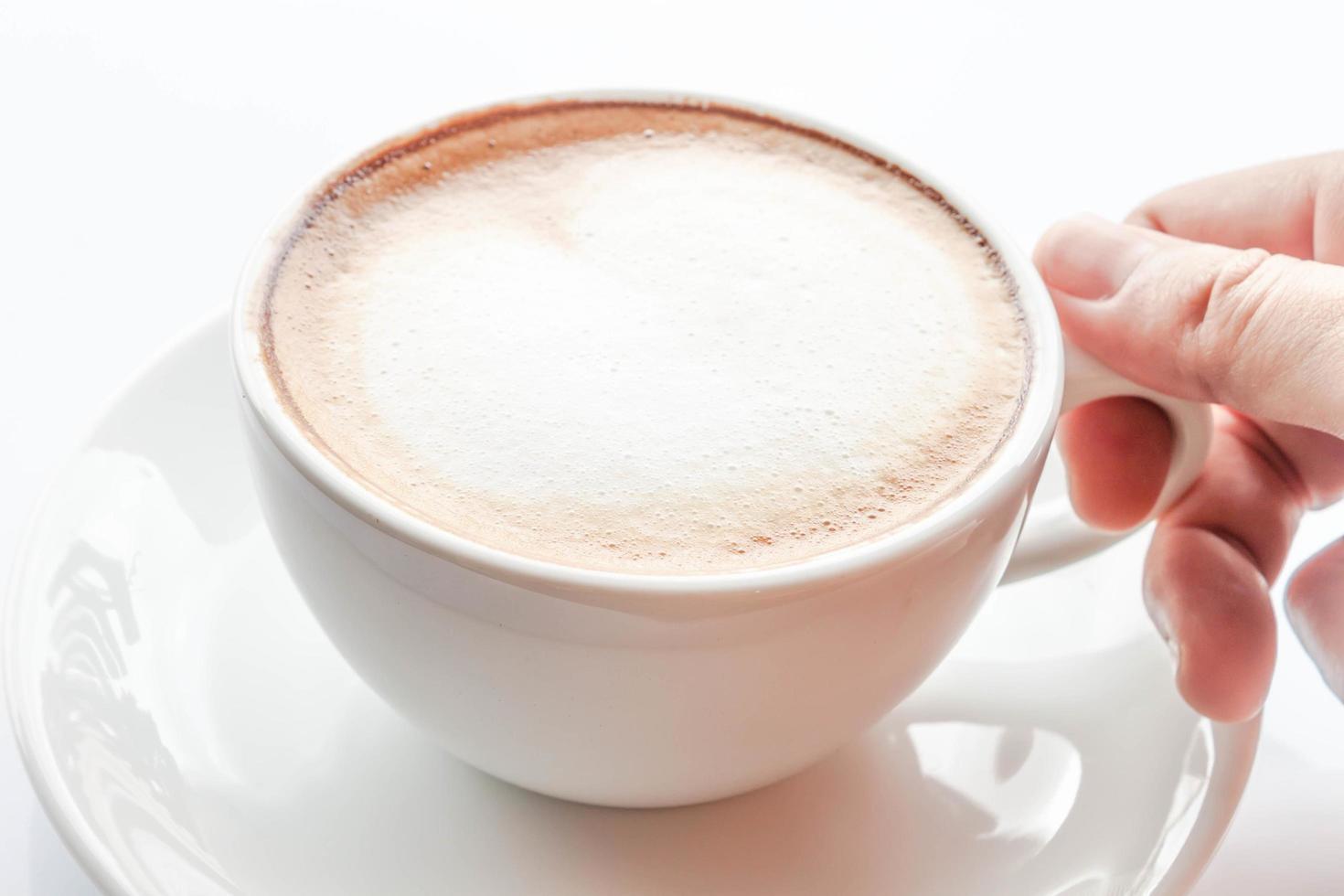 close-up de uma mão em uma xícara de café com leite foto