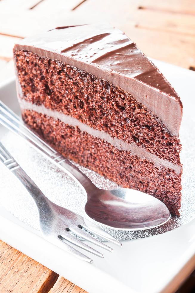 pedaço de bolo de chocolate servindo com garfo e colher foto