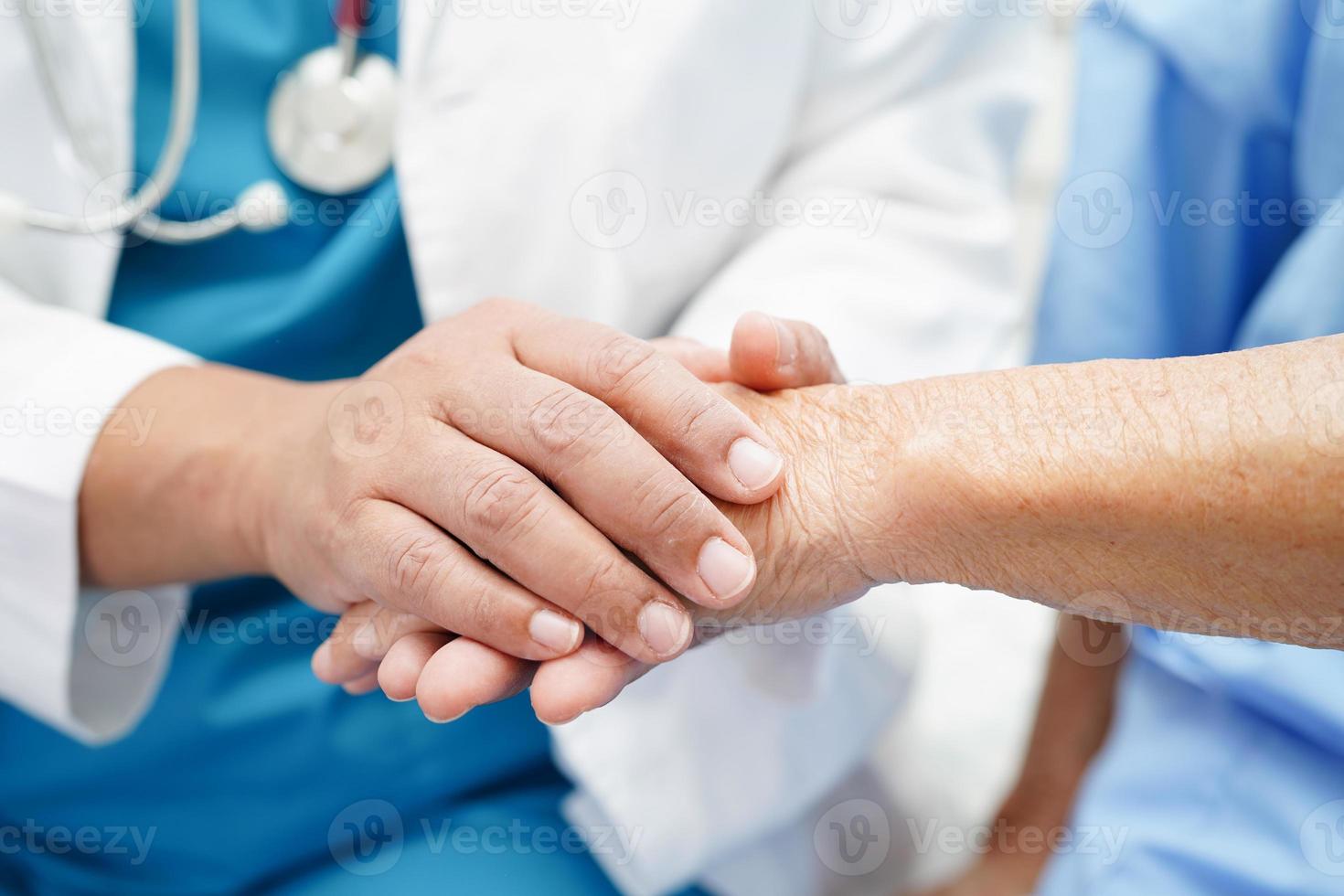 médico de mãos dadas paciente idosa asiática, ajuda e cuidados no hospital. foto
