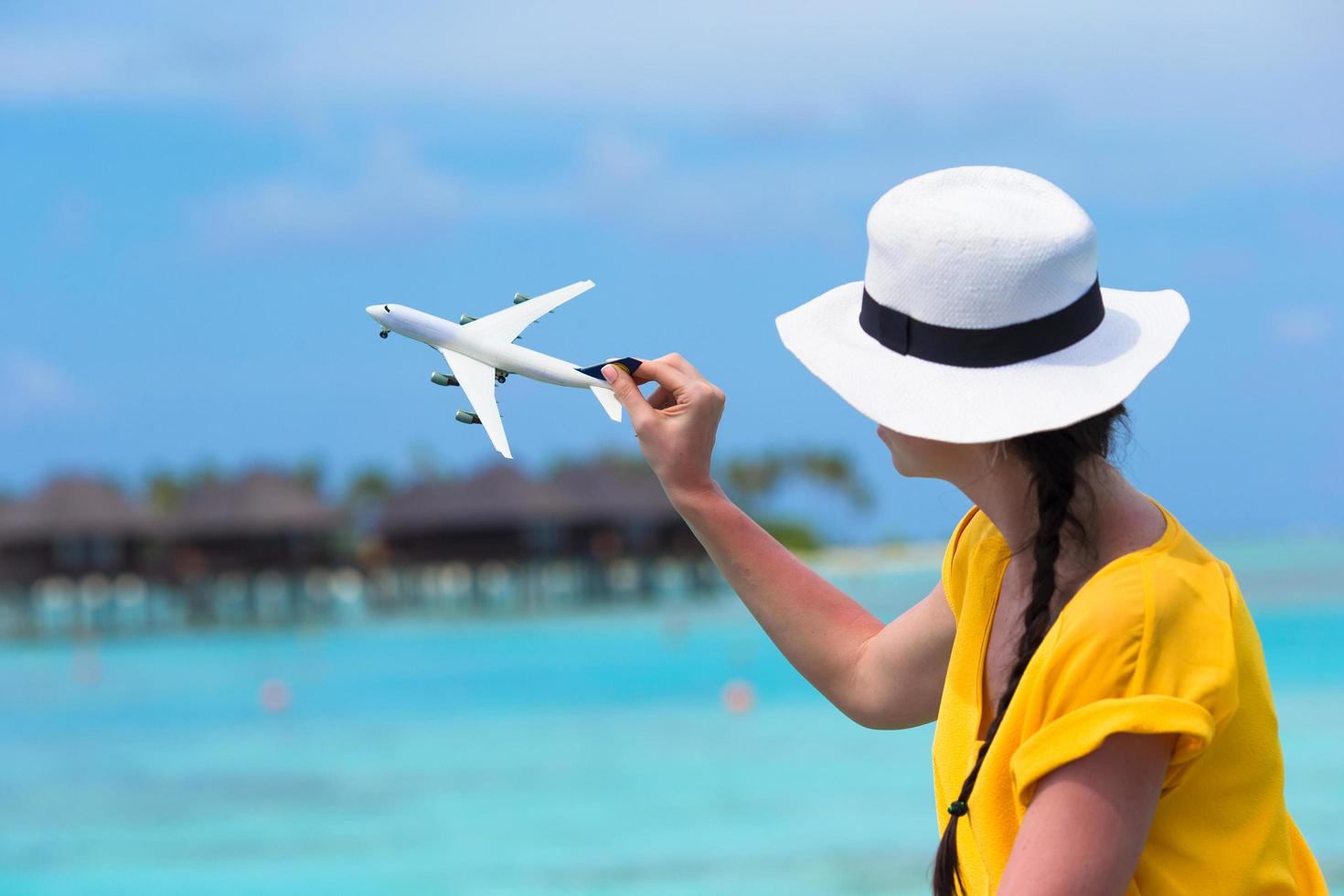 mulher brincando com um avião de brinquedo na praia foto