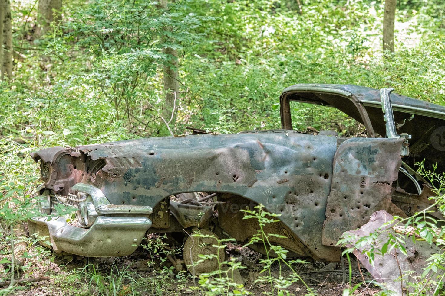 velho carro enferrujado abandonado na floresta com buracos de bala foto