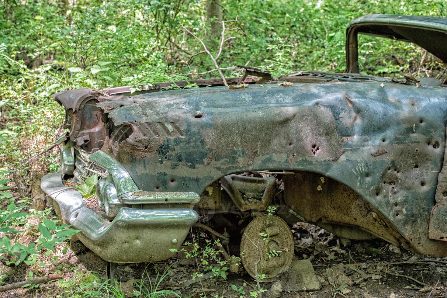 velho carro enferrujado abandonado na floresta com buracos de bala foto