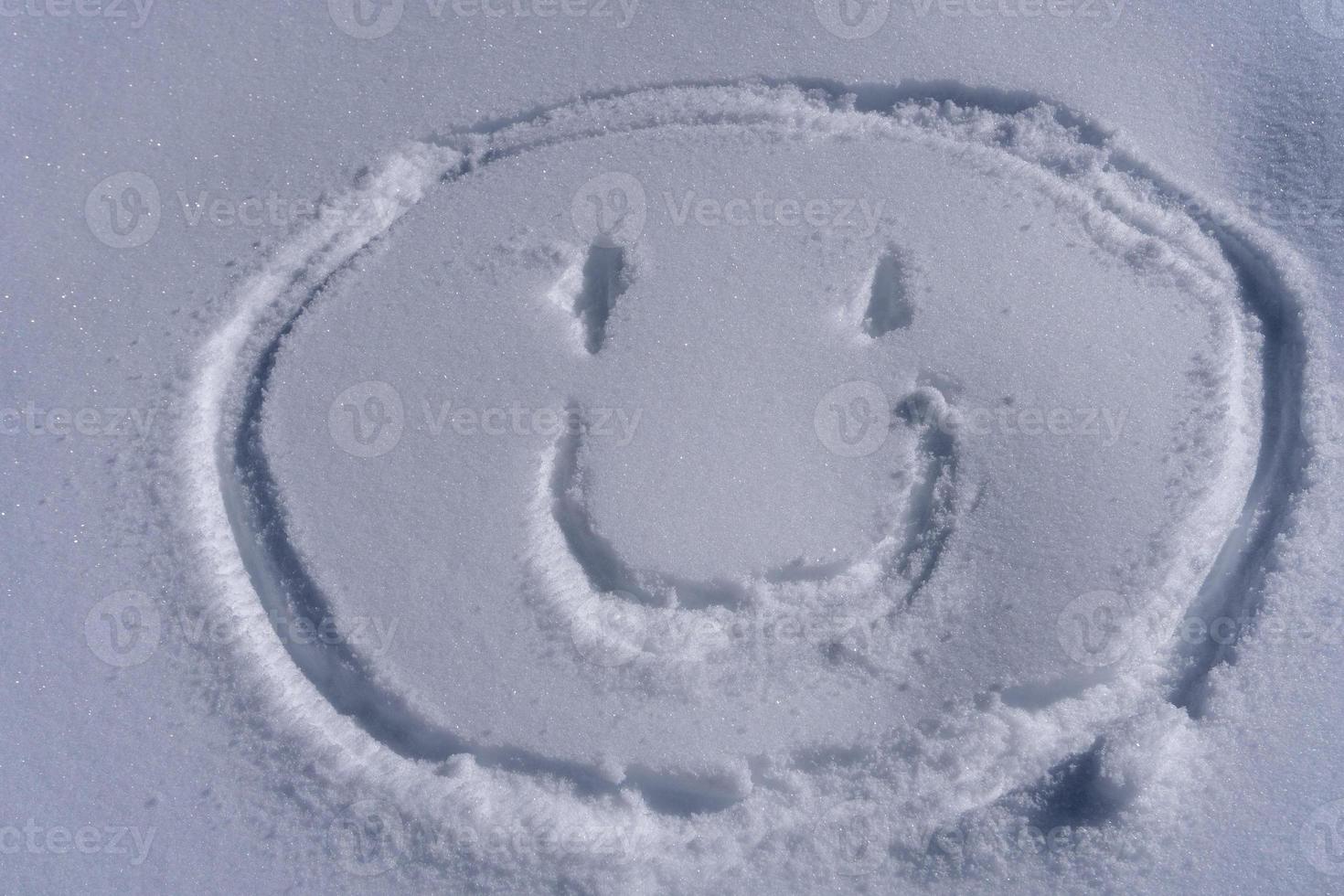 emoticon de rosto sorridente escrevendo na neve foto