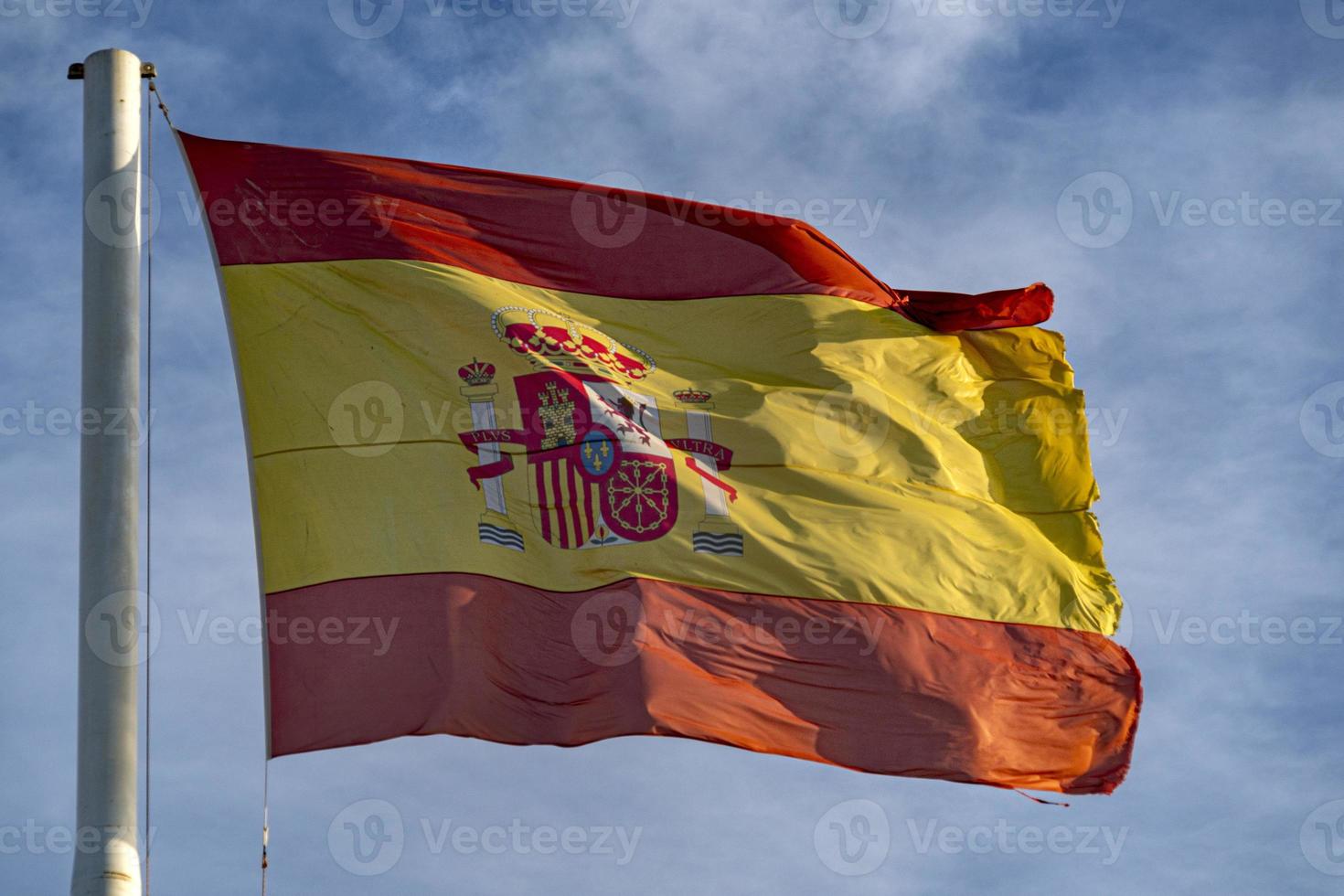 acenando a bandeira espanhola no céu foto