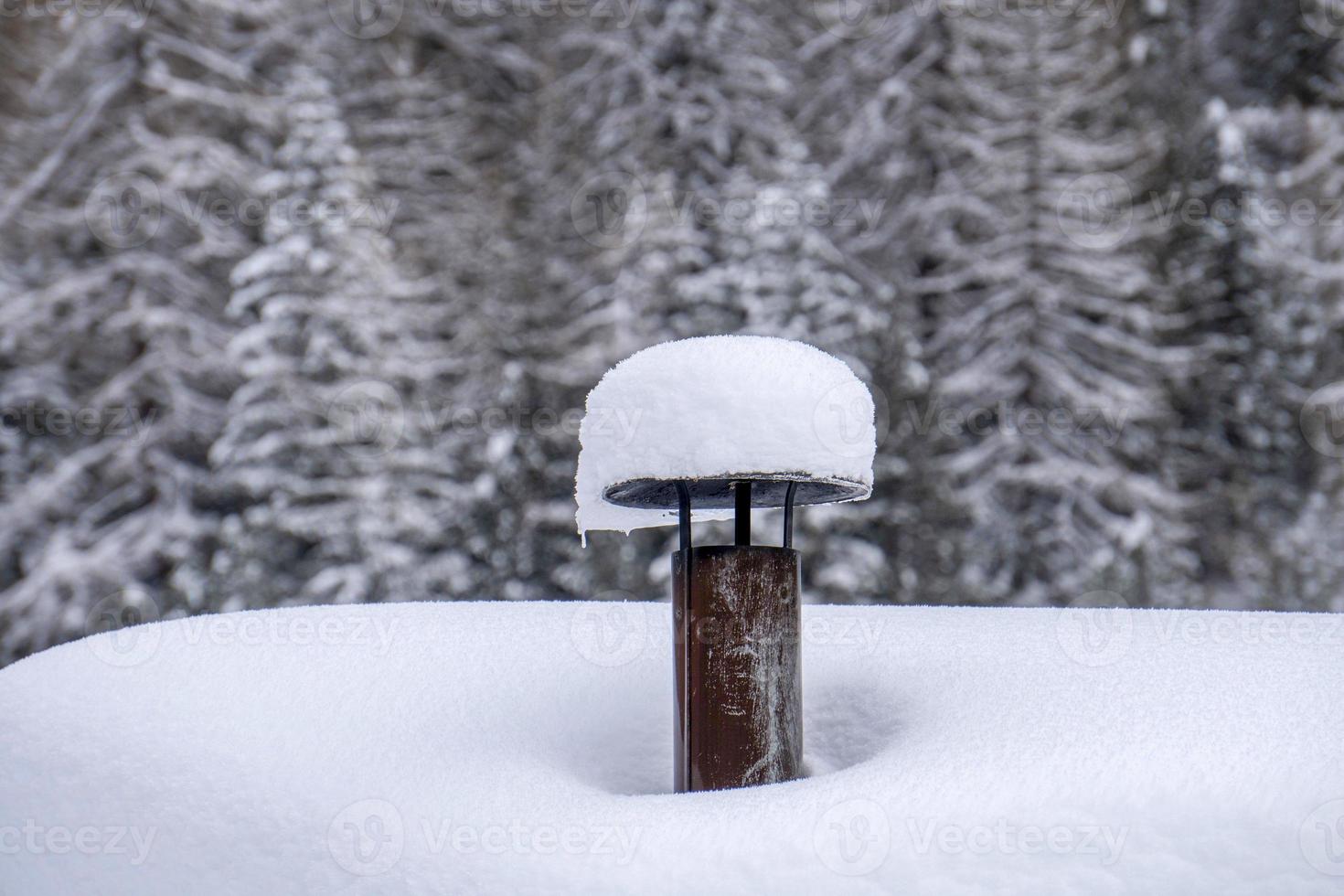 chaminé da casa da montanha coberta pela neve nas dolomitas foto