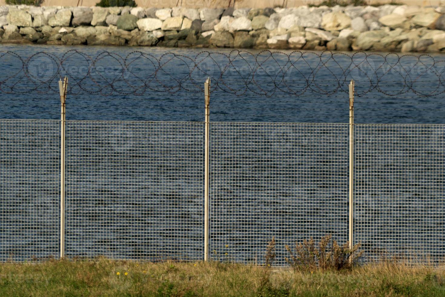 detalhe da cerca de arame farpado perto do mar foto