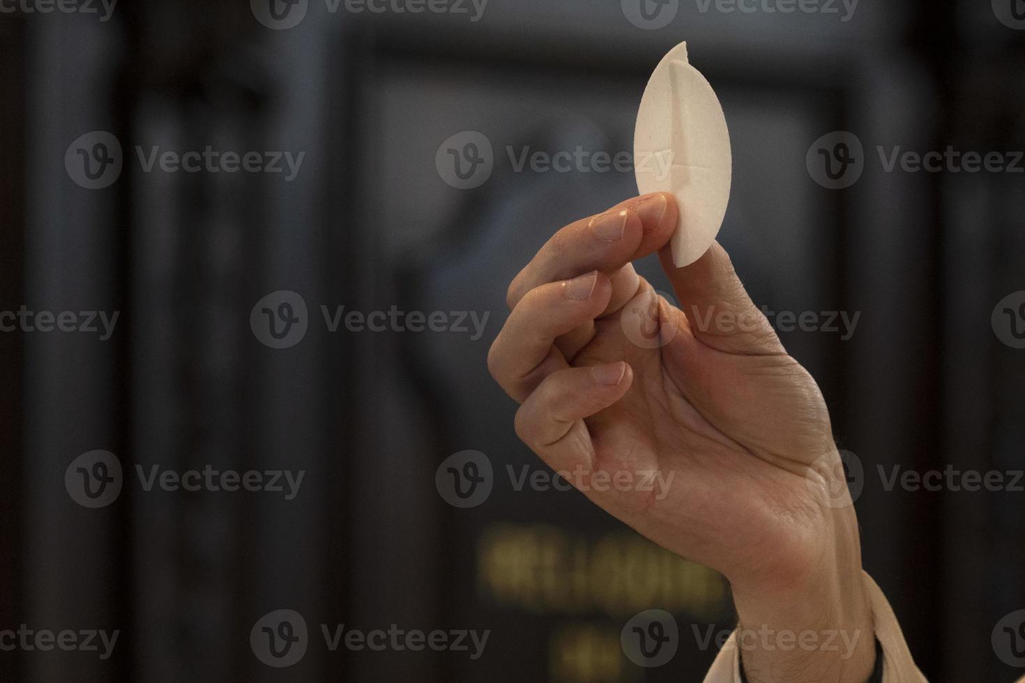 padre mão segurando hóstia consagrada foto