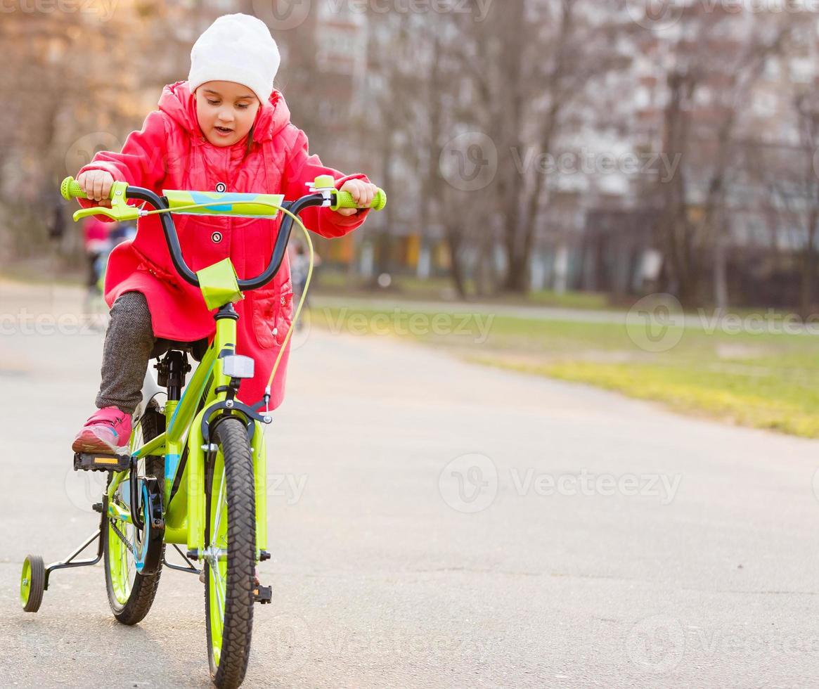 menina engraçada aprendendo a andar de bicicleta foto