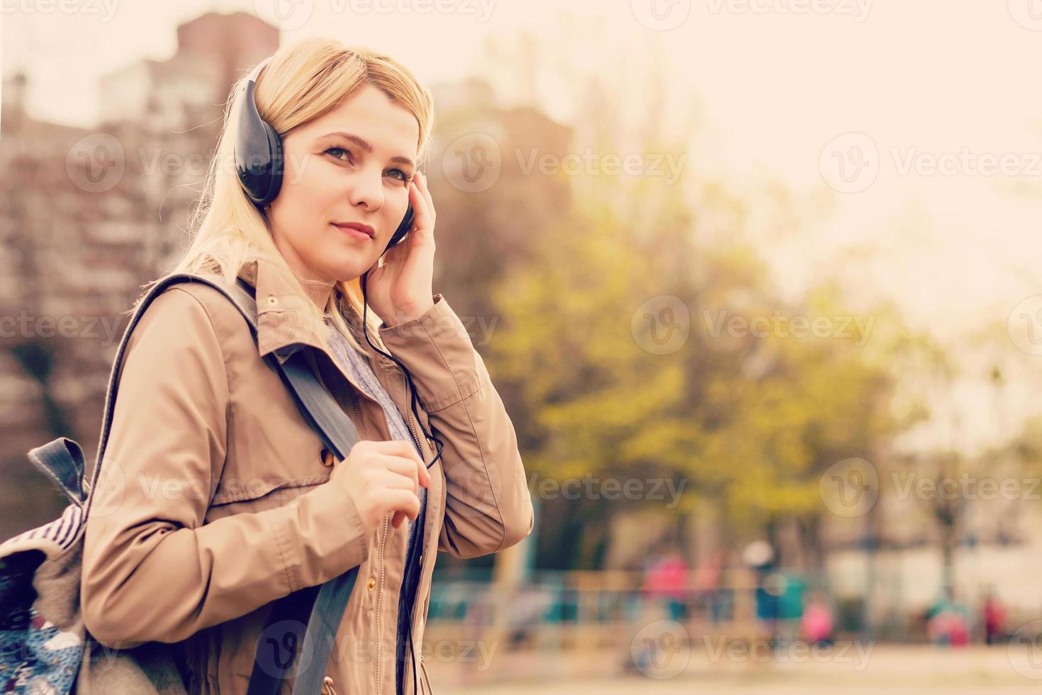 mulher jovem e bonita hipster ouvindo música com fones de ouvido na cidade foto