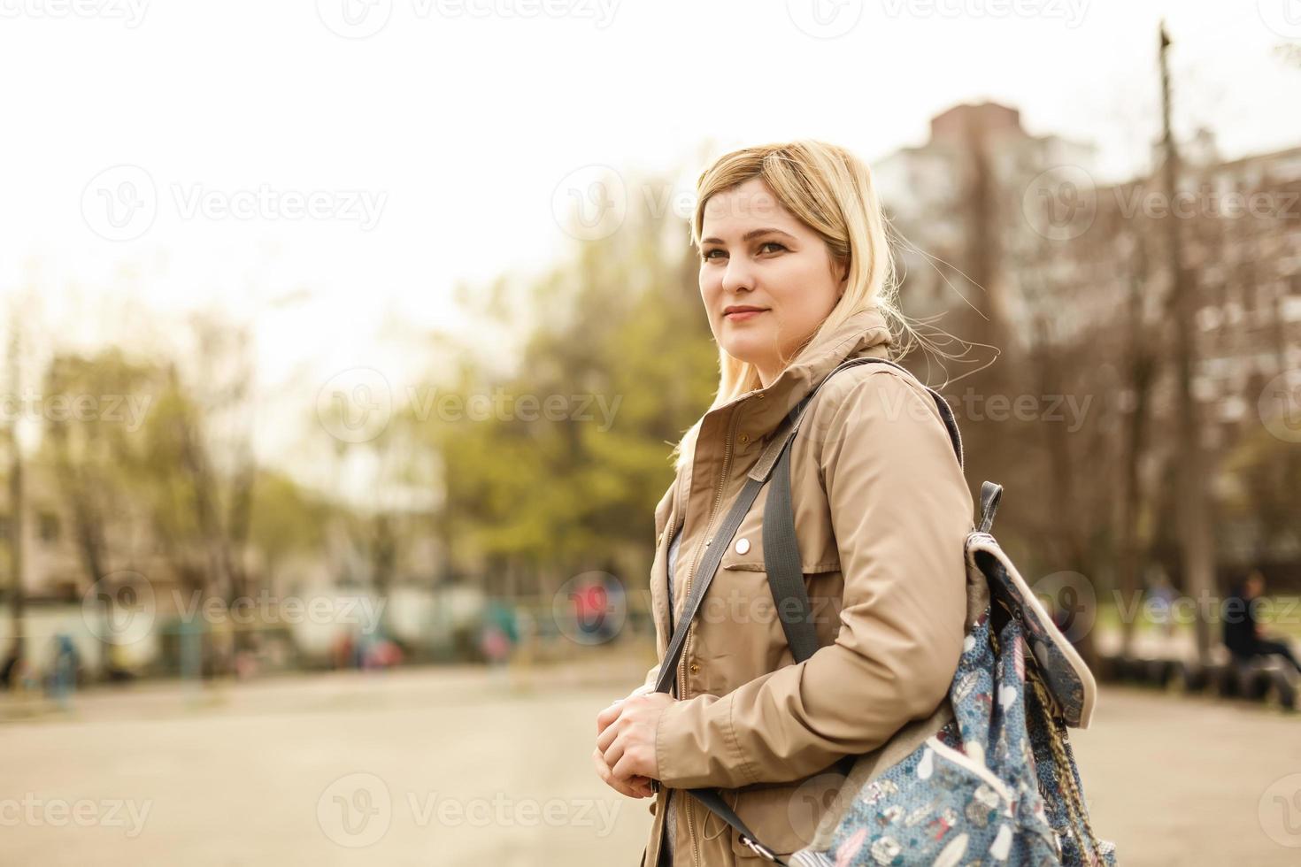 jovem hipster com mochila vintage verde-oliva, sentado na grama no parque. foto