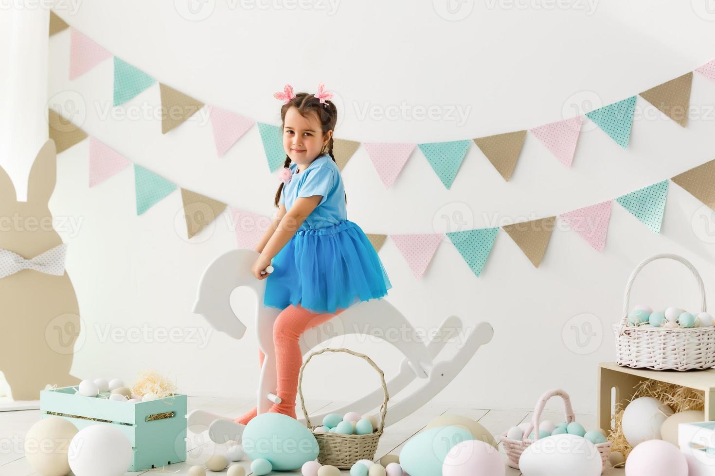se preparando para a páscoa. linda garotinha segurando um ovo de páscoa e sorrindo com decoração ao fundo foto