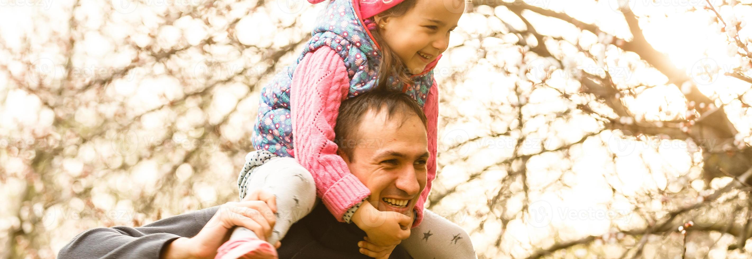 feliz alegre jovem pai com sua filha. pai e filho se divertindo ao ar livre no jardim do pomar, brincando juntos no parque de verão. pai com seu filho rindo e curtindo a natureza foto