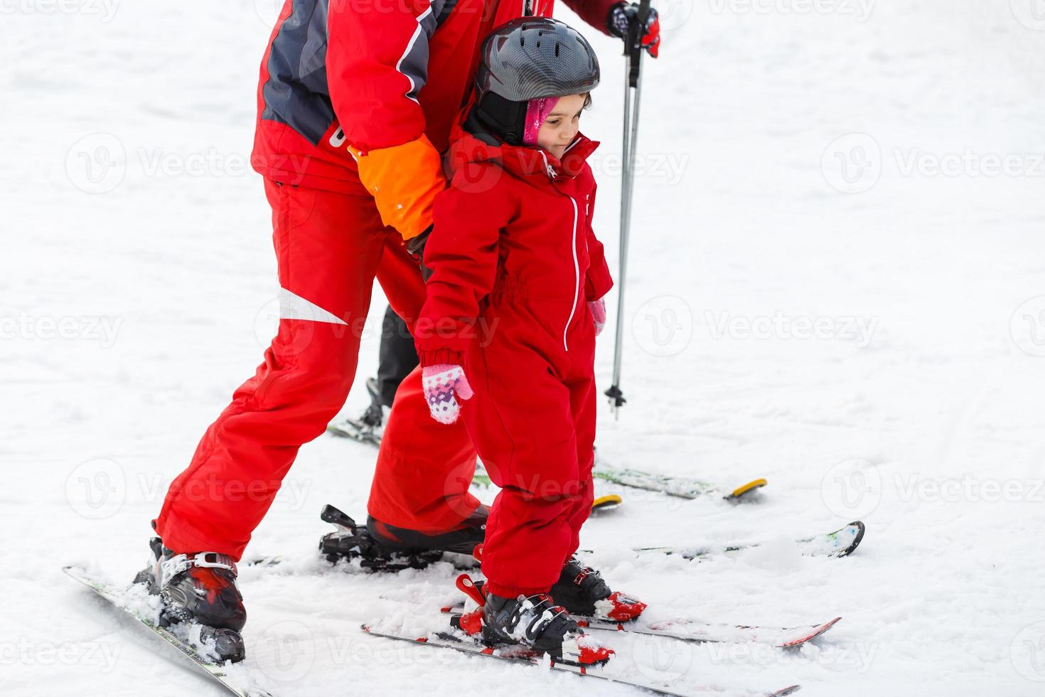 instrutor de esqui profissional está ensinando uma criança a esquiar em um dia ensolarado em um resort de encosta de montanha com sol e neve. família e filhos férias ativas. foto