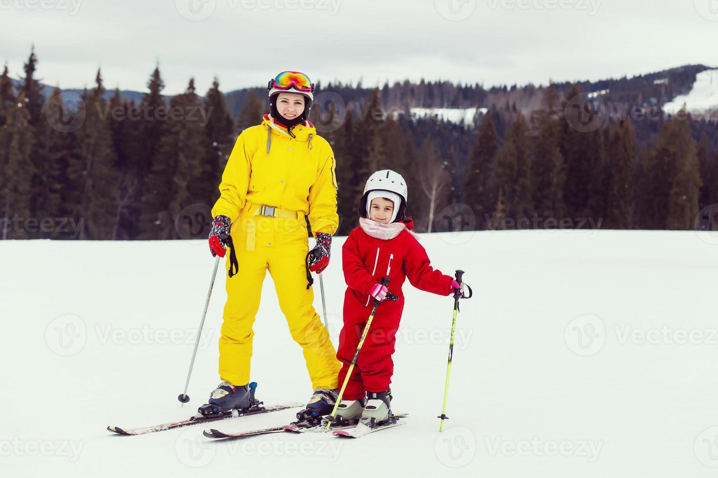 menina e uma mulher esquiadores no topo de uma encosta de montanha de neve indo esquiar foto