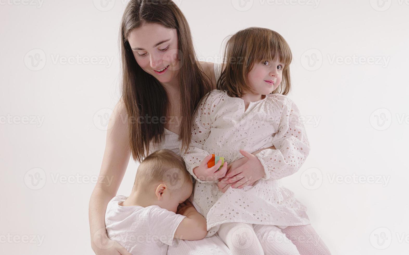 família no estúdio se divertindo isolado no fundo branco. pai, mãe e dois filhos se abraçam e sorriem foto