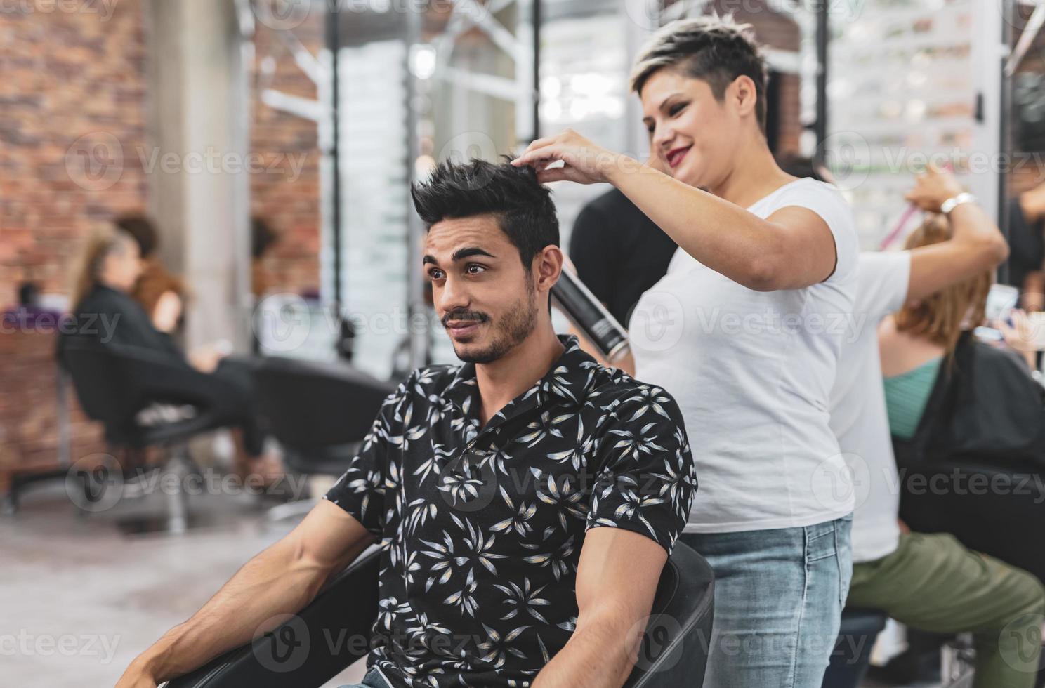 cabeleireiro profissional está cortando o cabelo masculino no salão de beleza. foto