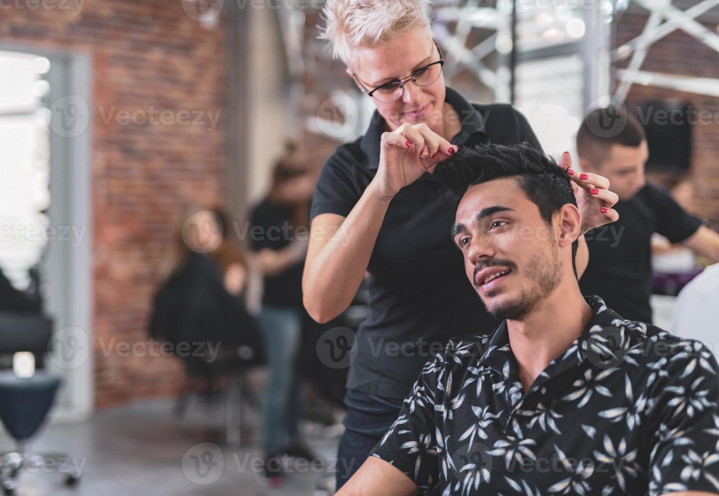 cabeleireiro profissional está cortando o cabelo masculino no salão de beleza. foto