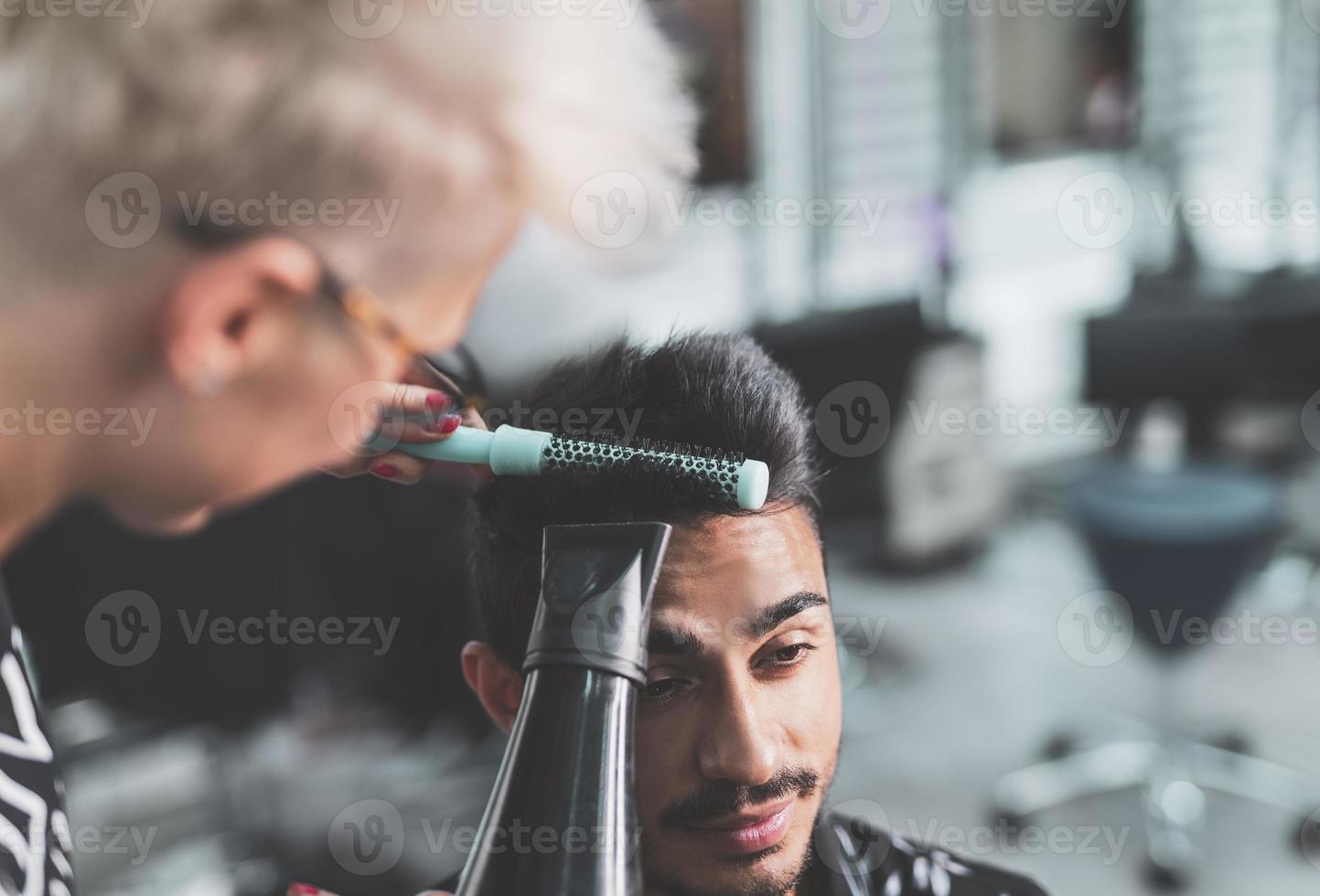 cabeleireiro profissional está cortando o cabelo masculino no salão de beleza. foto