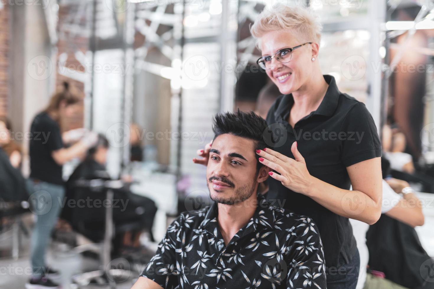 cabeleireiro profissional está cortando o cabelo masculino no salão de beleza. foto